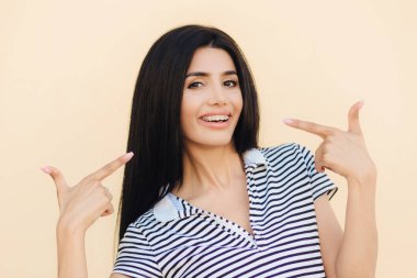 İyi görünümlü kapalı ağzını gülümseme ile genç erkek gösterdiğine uzun siyah saçlı, rahat çizgili t gömlek giymiş dişlerde gösterir parantez vurmuştu. İnsanlar, güzellik ve kavram güzel makyaj