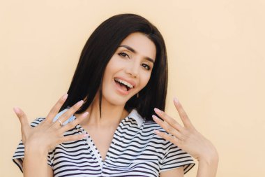 Hey bana bak! Güzel esmer genç kadın, sağlıklı cilt, makyaj, kameraya sevinçle gülümsüyor, diş diş teli takıyor, kendini iyi ruh hali içinde olmak elinde tutar. Güzellik kavramı