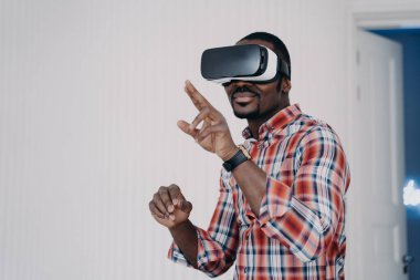 Sanal gerçeklik gözlüğü takan Afrikalı Amerikalı bir adam satın almayı test ediyor, sanal alemde alışveriş yapıyor. Video gözlüklü modern siyah adam video oyunu oynuyor, sanal nesnelerle etkileşimde, yüksek teknolojiden hoşlanıyor..