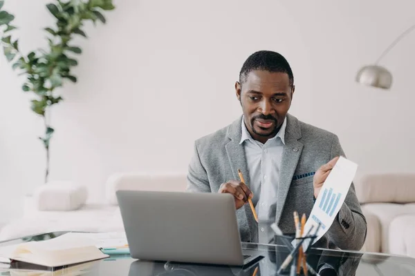 African american businessman showing data graph presenting to business partner by video call at laptop. Black male business person coach consulting client, discussing work project online.