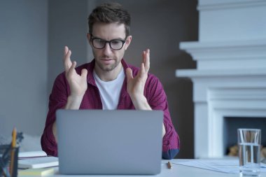 Ciddi odaklanmış bir öğretmen bilgisayar ekranına bakıyor ve uzaktan çalışırken konuşuyor. Günlük kıyafetlerle. E-öğrenme ve uzaktan eğitim kavramı