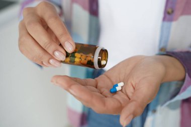 Diyet takviyesi, vitamin ya da ilaç alan kadın hapları yakın çekim. Kadının elleri, tedavi için ağrı kesici ya da uyku hapları almak için kavanozdan tıbbi kapsülleri avuç içine döker..