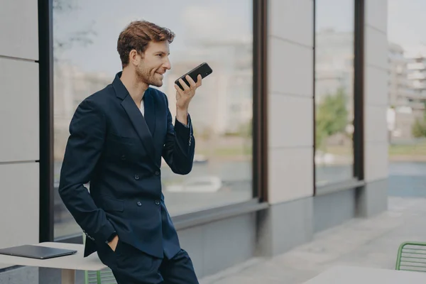 자신있는 사업가가 스마트폰으로 사용하여 하루를 조직하거나 메시지를 기록하고 스피커폰으로 말하며 — 스톡 사진
