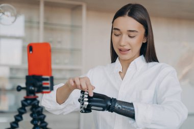 Evdeki sosyal ağlar için akıllı telefondan akıllı telefondan video çeken güzel engelli genç kız blogcu. Engelli insanlardan bahseden kadın etkili, canlı yayında biyonik protez gösteriyor.