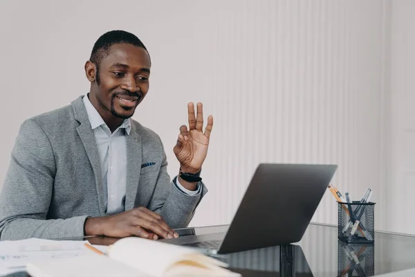 非裔美国男性经理在笔记本电脑上通过视频通话表示认可与客户交谈的姿态 微笑的黑人商人向在网上工作的员工展示可以签署的协议 — 图库照片