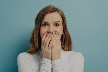 Büyüleyici genç kadın ağzını iki eliyle kapadı ve neşeli gözleri açıktı. Komik bir gülümsemeyle kameraya bakıyordu. Gördüklerine ya da duyduklarına inanamıyordu.