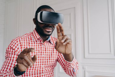 VR gözlük takan genç Afrikalı bir adam evinde oyun deneyiminin tadını çıkarıyor. Üç boyutlu gözlüklü esmer tenli bir iş adamı, modern ofiste dururken yenilikçi sanal gerçeklik teknolojisini kullanıyor.