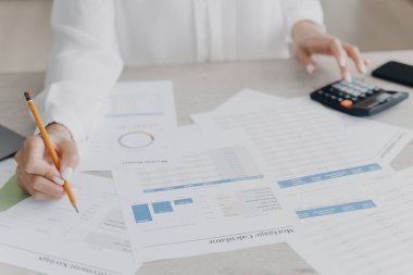 Çizelgelerde gösterilen kadın finansal analiz istatistiklerini kapat, harcamaları hesapla, ofis masasında bütçe planla. İş kadını finans, vergi sayıyor, iş yerinde hesap makinesi kullanıyor..