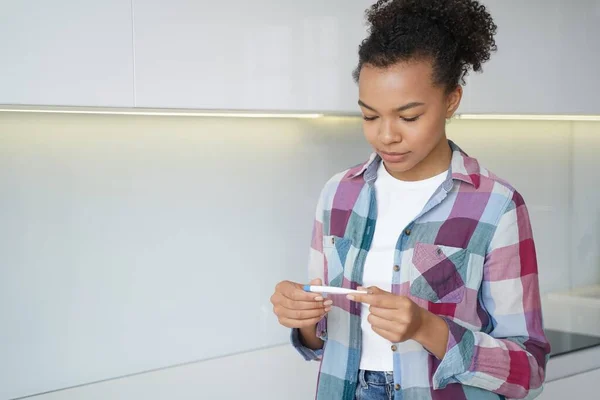 Pregnancy checking home test. African american teenage girl gets pregnancy test result. Satisfied young spanish woman is looking at the stripes. Baby planning and contraception concept.
