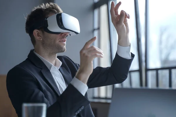 Cyberspace in business. Excited man office worker wearing vr goggles touching objects with hands in digital world, amazed businessman in 3d glasses interacting with virtual reality at work