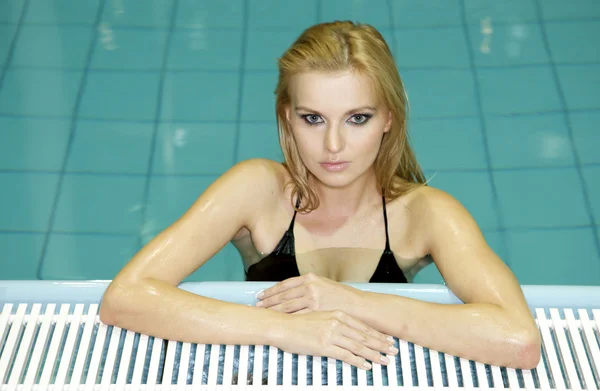 Schöne junge Frau steht in einem Swimmingpool — Stockfoto