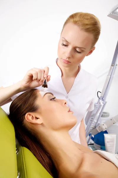 Mujer joven recibiendo tratamiento de máscara de piel de belleza en su cara con — Foto de Stock