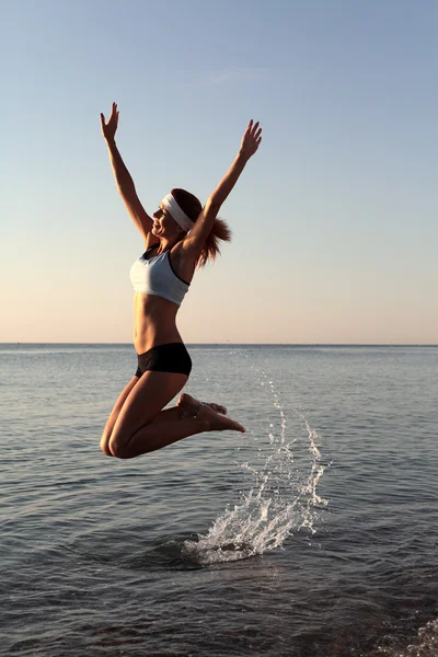 Gelukkig jonge vrouw is springen in het strand — Stockfoto