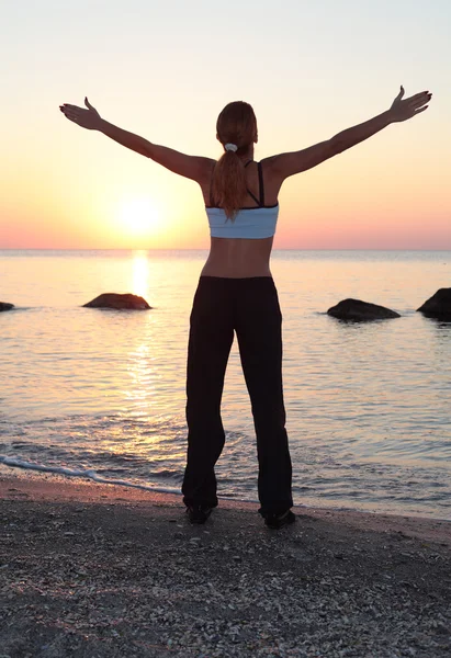 Jonge mooie vrouw tijdens fitness op zee strand — Stockfoto