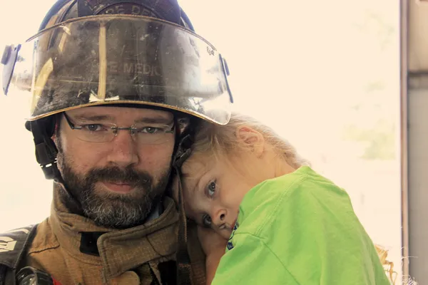 Nahaufnahme eines Feuerwehrmannes, der ein kleines Mädchen hält — Stockfoto