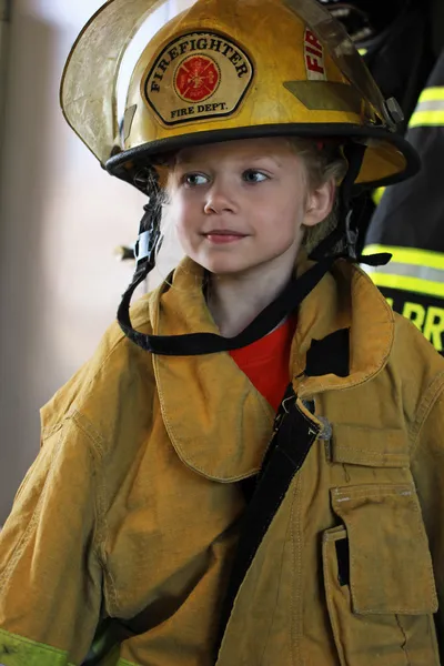 Giovane ragazza in attrezzatura pompiere Immagini Stock Royalty Free