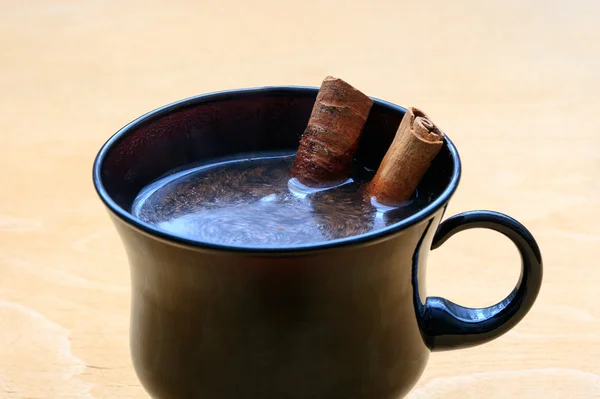 Tasse Kaffee mit Zimtstangen auf Holztisch — Stockfoto