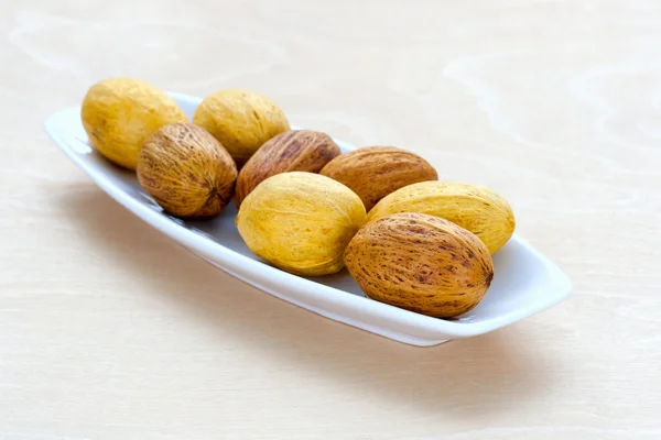 Nueces marrones tiradas en fila en una bandeja — Foto de Stock