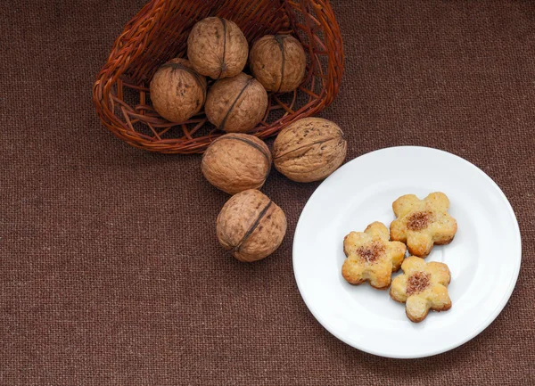 Rieten mand met noten en gebak op een plaat — Stockfoto