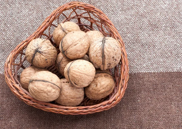 Walnuts in the old wicker basket on burlap — Stock Photo, Image