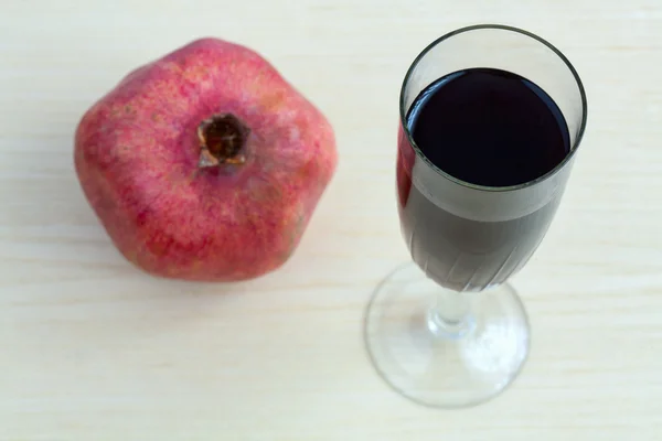 Goblet of wine and a pomegranate on the table — Stock Photo, Image