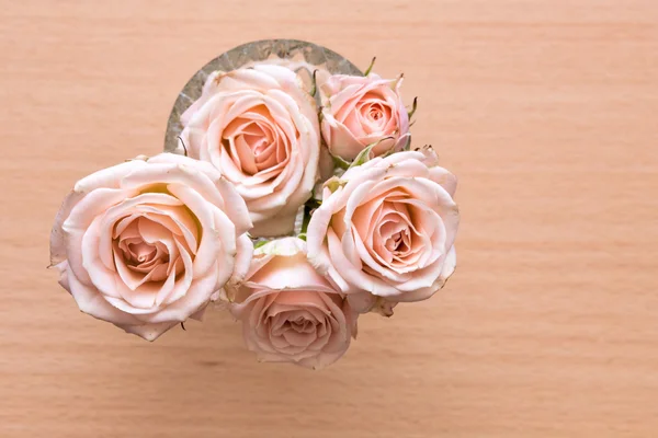 Rosas rosadas en un jarrón sobre un escritorio de madera — Foto de Stock