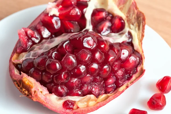 The cut pomegranate and grains on a plate — Stock Photo, Image