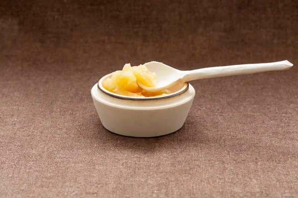 Pot of honey and wooden dipper on a cloth — Stock Photo, Image