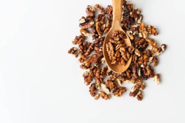 Tahta kaşıkta cevizler beyaz bir masaya saçılmış. Yakın plan, gürültü, bulanıklık, seçici odaklanma