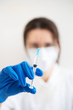 Elinde şırıngayla genç bir doktor. Kapalı alandaki doktor aşı yapıyor. Tıp bürosundaki bir kadın. Grip ve virüslere karşı aşı