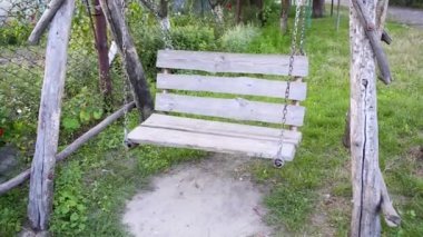 Bahçedeki tahta ve kütüklerden sallanan güzel ahşap salıncaklar. Boş ahşap salıncak koltuğu. Oyun bahçesinde, yaz bahçesinde zincirlerde asılı.