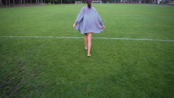 Beautiful girl start jogging running doing morning exercise on football field. Pretty young woman run in blue shirt fluttering in the wind on summer day. Female athlete train on rural soccer pitch. — Stock Video