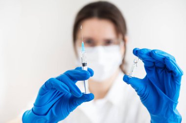 Elinde şırınga ve aşı olan genç bir doktor. Kapalı alandaki doktor aşı yapıyor. Tıp bürosundaki bir kadın. Grip ve virüslere karşı aşı