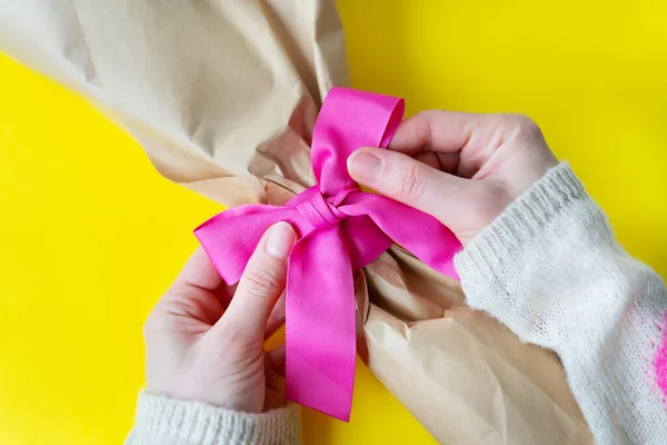 Вид Сверху Женских Рук Вяжущих Букет Розовой Лентой Подарками Желтом — стоковое фото
