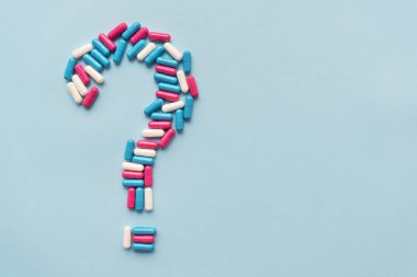 Mavi arka planda üç farklı renkli vitaminden oluşan bir soru işareti. Sağlık sorunu ve tedavi