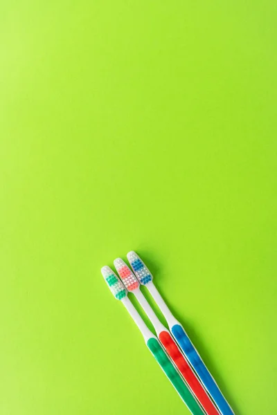 五颜六色的牙刷在绿色的背景上 是牙齿护理和口腔卫生的概念 登记的地点 — 图库照片