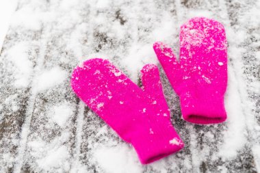 Beyaz kar üzerinde pembe eldivenler, üst manzara. Kış açık hava oyunları