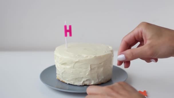 Cooking and decoration of cake candles in the form of letters. Girl hand pastry chef in the kitchen decorating white cream cake word - happy. Young woman in kitchen makes beautiful birthday cake. — Video