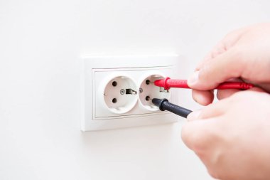 Prizdeki voltajı profesyonel bir dijital multimetre ile ölçüyorum. Profesyonel elektrikçi, prizleri yerleştirme süreci. Yakın çekim, seçici odak, gürültü