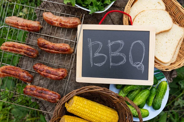 Barbecue inscription on chalkboard, grilled sausages, corn,bread. Outdoor recreation concept