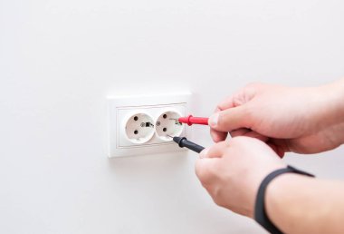 Prizdeki voltajı profesyonel bir dijital multimetre ile ölçüyorum. Profesyonel elektrikçi, prizleri yerleştirme süreci. Yakın çekim, seçici odak, gürültü