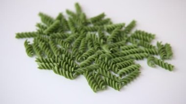 Tam tahıllı, koyu yeşil, pişmemiş fusilli makarna. İtalyan makarnası beyaz bir masada yığılıp kaldı. Akdeniz mutfağı kavramı