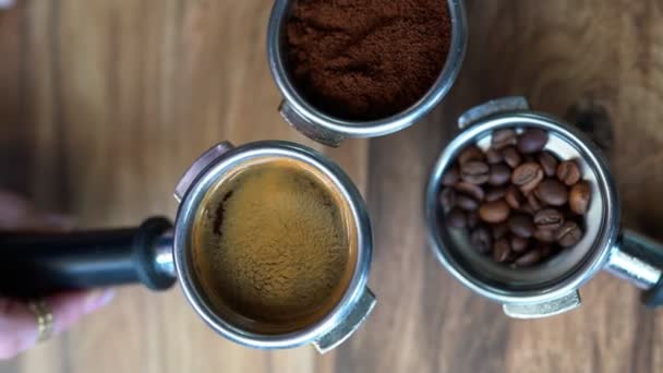手にバリスタは 新鮮なコーヒーを保持し 攪拌します 自然光の陰で 木の背景にポートフィルターやコーヒー豆のバスケット内のコーヒーグラウンドのタンプパック — ストック動画