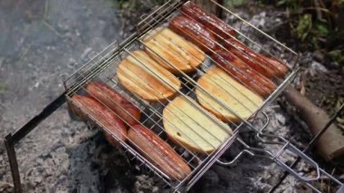 Izgarada beyaz ekmek dilimli ızgara sosis. Temiz havada dinlenme, ızgarada sosis kızartma, barbekü. Barbeküde kızartılıyor. Sıcak duman ürünlerden geçer