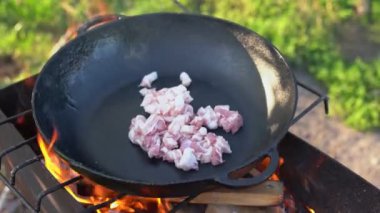 Büyük bir tavada domuz yağıyla taze et kızartmak bahçede ateş yakmak. Kızartma tavasında pişen yağlı organik domuz dilimleri. Paella için BBQ eti hazırlıyorum.