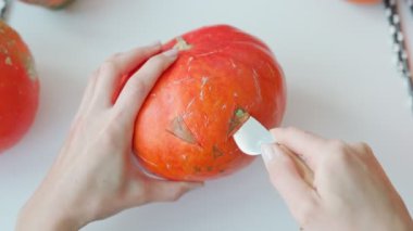 Girl preparing a scary pumpkin in autumn holidays. Woman making the Halloween attribute with your hands. Hands cut out eye with knife. Jack-O-Lantern creation. Do it yourself - creative realisation