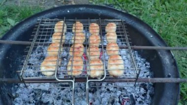Sosis ızgarası, yukarıdan manzara ızgarada ızgara sosis, bahçede yakın plan. Tavuk sosisleri dışarıda ızgarada pişiyor. Izgara ızgara, sulu sosisler, mangal kömürü ve ızgara.