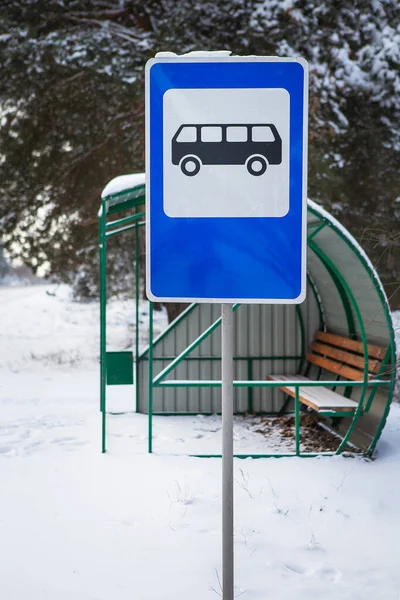 Bus stop in the middle of a beautiful winter road in the middle of the forest with a bus stop sign