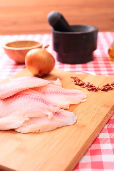 Rauwe vis tilapia op snijplank en specerijen — Stockfoto