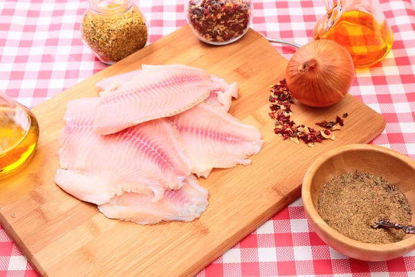 Raw fish tilapia on cutting board and spices — Stock Photo, Image